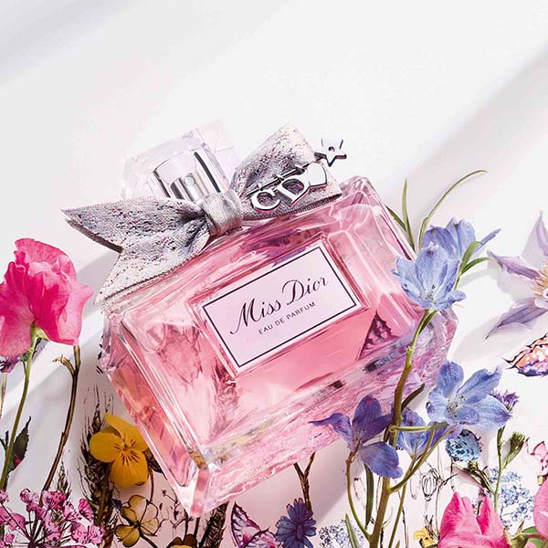 Miss Dior perfume bottle on its side with flowers surrounding it