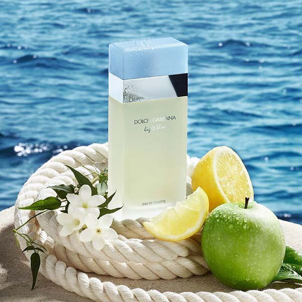 Dolce Gabbana light blue edt in rope surrounded by ingredients of lemon apple and jasmine